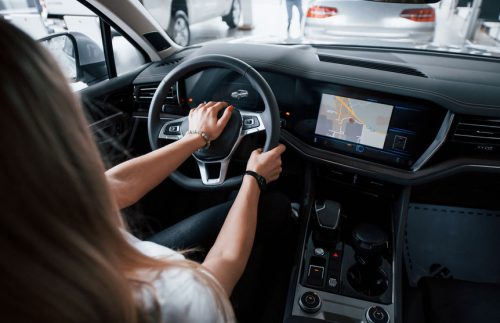 Using Gps. Girl In Modern Car In The Salon. At Daytime Indoors. Buying New Vehicle